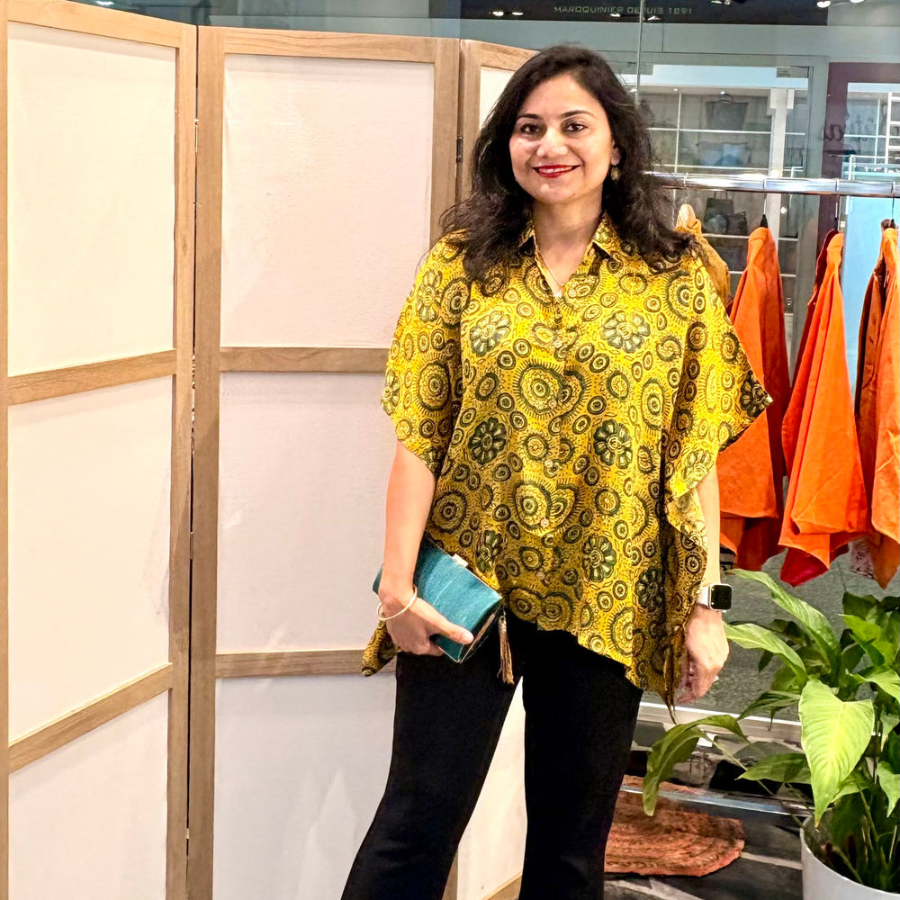Zenia wearing Les Sûtras  Modal Silk Kaftan - Block Print Top - Yellow paired with black trousers and green clutch. 