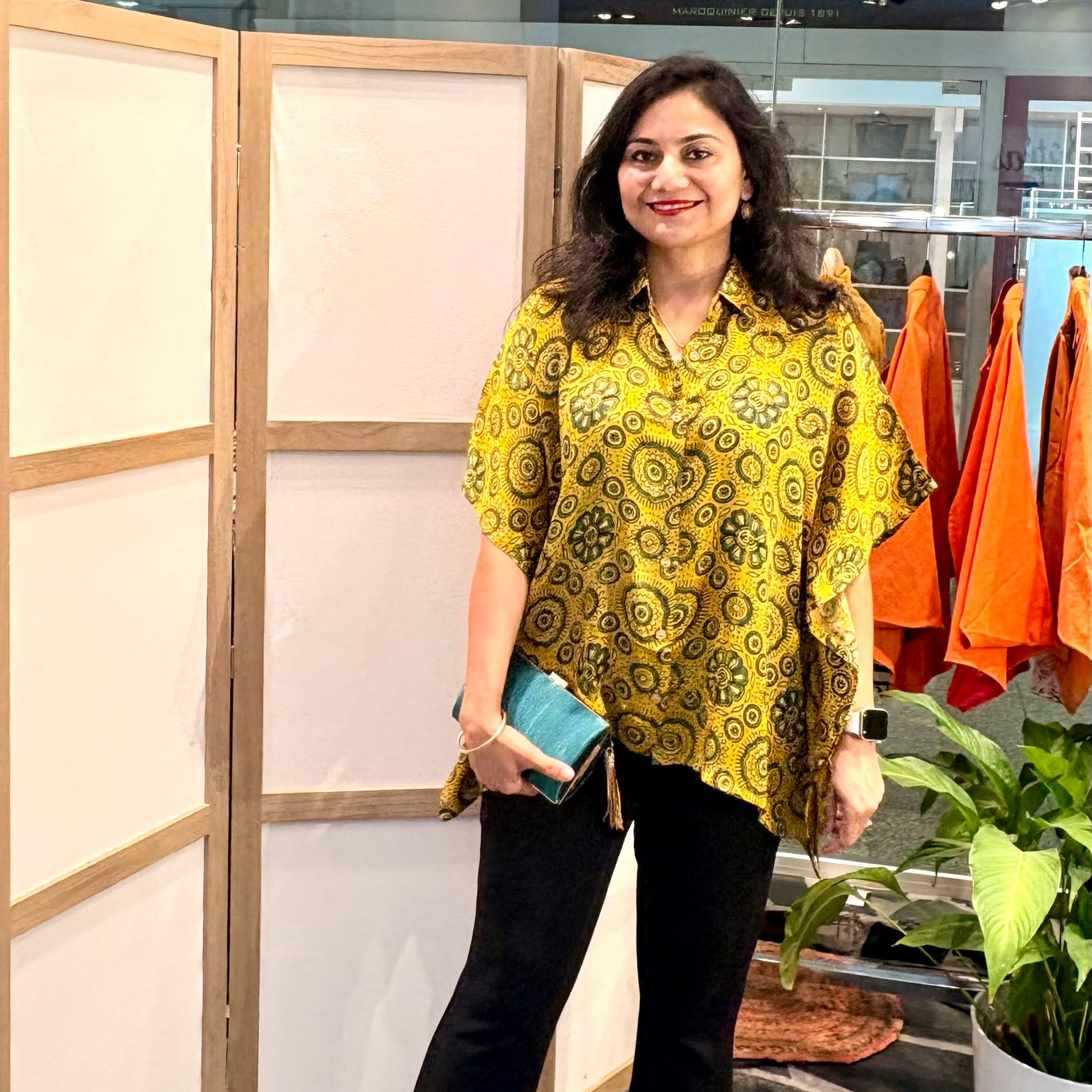 Zenia wearing Les Sûtras  Modal Silk Kaftan - Block Print Top - Yellow paired with black trousers and green clutch. 