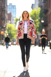 Woman walking on a city street wearing a Les Sûtras Velvet Suzani_-Embroidered_Jacket_-_Light_Pink_  jacket.