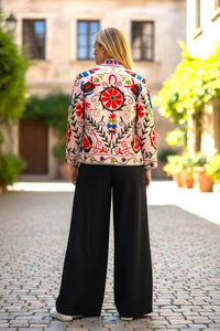 Model wearing a colourful embroidered Les Sûtras Velvet Suzani -Embroidered_Jacket_-_Light_Pink.