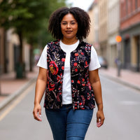 Woman walking on a street wearing a floral vest, white shirt, blue jeans, and white sneakers.
